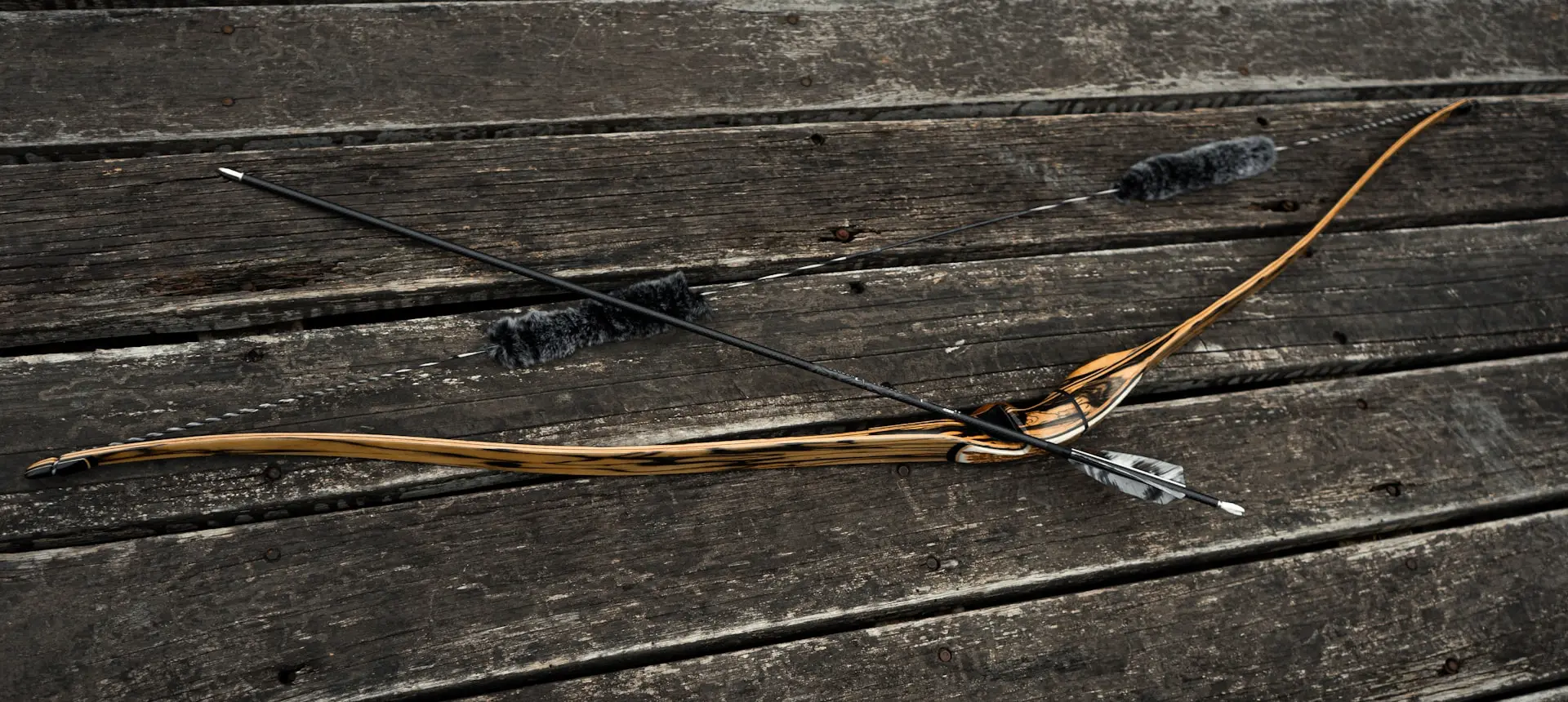 a bow and arrow laying on a wooden bench